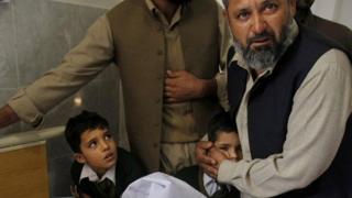 A Pakistani man comforts a student standing at the bedside of a boy who was injured in a Taliban attack on a school in Peshawar, Pakistan, Tuesday, December 16, 2014