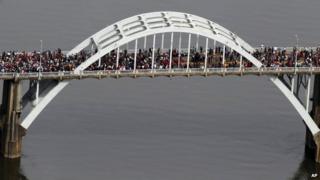 Толпы людей движутся в символической прогулке по мосту Эдмунда Петтуса, в воскресенье, 8 марта 2015 года, в Сельме,