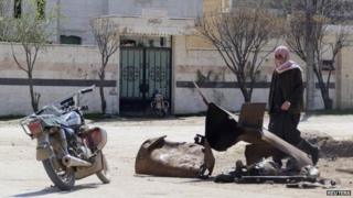 A Syrian man stands next to the remains of a barrel bomb that activists say was dropped on the town of Sarmin on the night of 16 March 2015