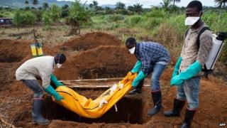 Volunteers in protective suit burry the body of a person who died from Ebola in Waterloo, some 30 kilometers southeast of Freetown, Sierra Leone, on October 7 2014