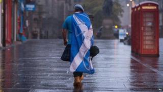 A lone "YES" campaign supporter walks down a street in Edinburgh
