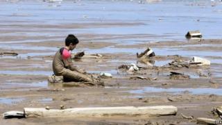 A child sits by wreckage after torrential floods and rains in Chanaral on 27 March 2015