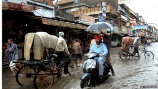 Indian commuters make their way along a flooded street in Amritsar, after heavy monsoon rainfall struck the northern Indian city