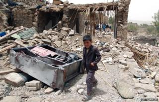 A Yemeni boy walks past the rubble of destroyed houses in the village of Bani Matar, 70 kilometers (43 miles) West of Sanaa, on 4 April, 2015