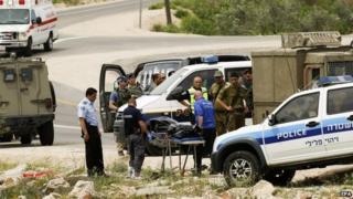 The body of a Palestinian man who was shot dead after stabbing two Israeli soldiers is removed from the scene of the attack near Sinjil in the West Bank (8 April 2015)
