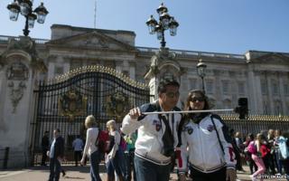 A couple take a selfie in front of Buckingham Palace