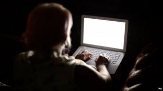 A person using a laptop computer in the dark