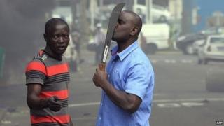 Иностранный гражданин держит мачете, чтобы защитить себя после столкновений между группой местных жителей и полицией в Дурбане 14 апреля 2015 года в связи с продолжающимся насилием в отношении иностранных граждан в Дурбане, Южная Африка