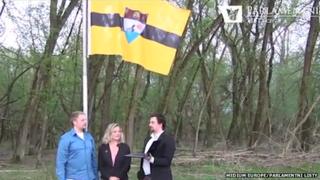 The "founders" of Liberland standing in front of the raised flag