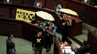 Pro-democracy lawmakers Raymond Chan (2nd R) chants slogans as he and Albert Chan (R), carrying yellow umbrellas, a symbol of the Occupy Central movement, leave to boycott Hong Kong Chief Secretary Carrie Lam during a Legislative Council meeting in Hong Kong April 22, 2015.