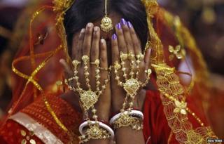 A bride covers her face as she waits to take her wedding vow at a mass marriage ceremony at Bahirkhand village, north of Kolkata February 8, 2015.