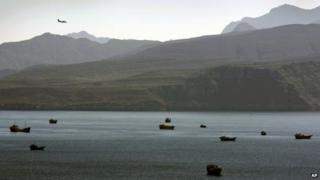 In this Jan. 19, 2012 file photo, a plane flies over the mountains in south of the Strait of Hormuz as the trading dhows and ships are docked on the Persian Gulf waters near the town of Khasab, in Oman