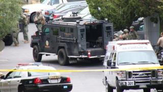 SWAT teams and other police officers wait during the standoff