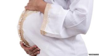A pregnant woman holding her stomach