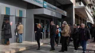 People wait to use an ATM in Greece
