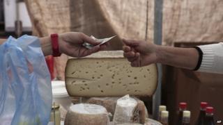 Consumer buys cheese at Athens market (30 May)