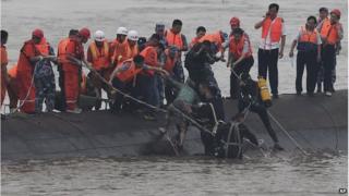 Rescuers help a woman to safety from the upturned boat (2 June 2015)