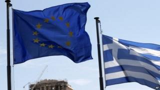 A Greek and a European Union flag billow in the wind as the ruins of the fifth century BC Parthenon temple are seen in the background on the Acropolis