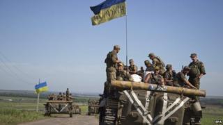 Ukrainian servicemen ride on an armoured military vehicle