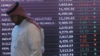 A Saudi investor walks past a screen