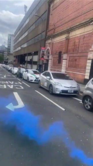 A blue smoke flare next to convoy of taxis