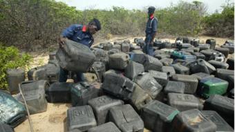 Policías con bidones de combustible confiscado.