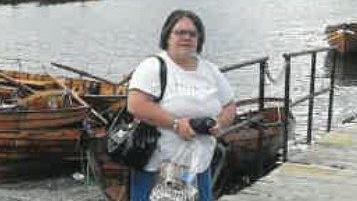 A low quality photo showing a woman standing in front of some boats