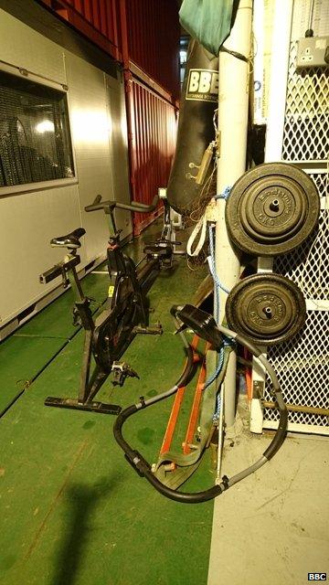 Picture of a black exercise bike and weights in the foreground.