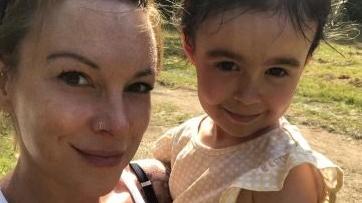 A smiling woman is holding her daughter up to the camera 