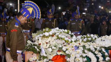 Central Reserve Police Force (CRPF) officers bow to pay tribute next to a coffin containing the remains of their colleague Bablu Santra in Howrah, West Bengal