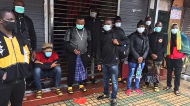 Lidé stojící před obchodem s maskami na obličeji