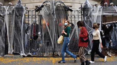 Three women walk past a Halloween display