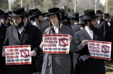 超正統派ユダヤ人の抗議者（その一部は、イスラエルの存在に反対する、反シオニスト超正統派のユダヤ人の小さな一派、Neturei Kartaに属しています）。's existence, hold placards during an anti-zionist demonstration outside the US consulate in Jerusalem