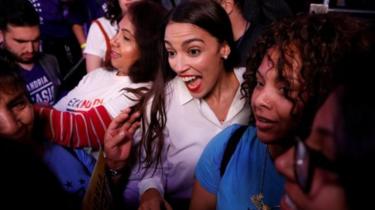 Alexandria Ocasio-Cortez (dhexda) waa gabadha ugu da'da yar ee Koongareeska gashay