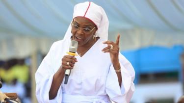 Grace Mugabe, with a microphone speaking, dressed all in white in November image