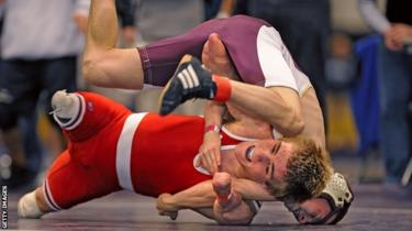 A young wrestler with no legs attempting to pin his opponent.