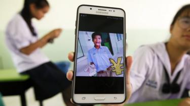 A Thai student shows an image of her classmate Panumas Sangdee,