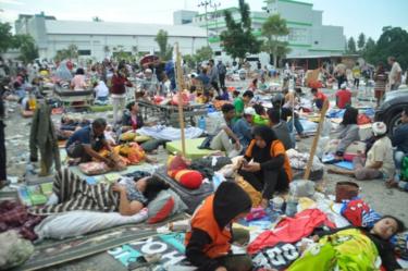 Dozens of patients sit and lie outside a hospital as medical teams try to help them