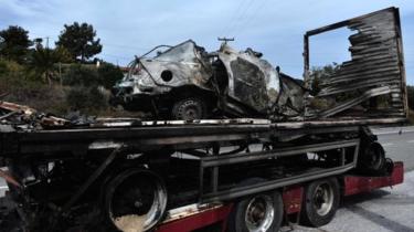 The burned-out car is retrieved near Kavala