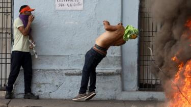 A demonstrator hits a barbed wire while clashing with security forces in Urena, Venezuela