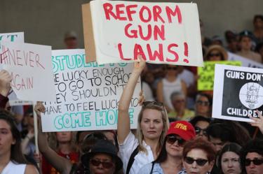 A woman carries a sign reading "reform gun laws", at the rally in Fort Lauderdale