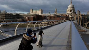 de mens neemt een foto van zijn hond op een verlaten Millenniumbrug in Londen