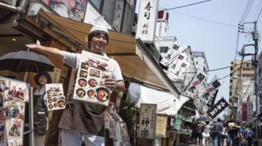 A man stands outside a seafood restaurant in Tsujiki