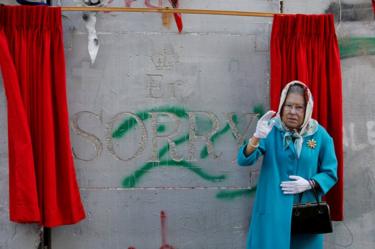 An actor dressed as Britain's Queen Elizabeth II, gestures during an event ahead of the anniversary of the Balfour Declaration, outside Banksy's Walled Off Hotel in the West Bank city of Bethlehem, 1 November 2017.