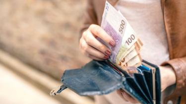 Woman taking Euro notes out of a black wallet
