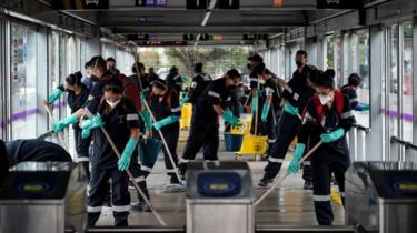 Workers wash and disinfect a bus station, as a measure to prevent the spread of the new Coronavirus, COVID-19, in Bogota