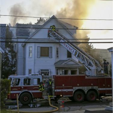 Firefighters using ladders at a house on fire