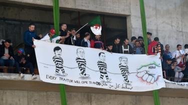People hold a banner calling the president, the general secretary of the General Union of Algerian Workers (UGTA), the chairman of Algeria's Forum des chefs dentreprises (FCE), and the former prime minister "traitors".