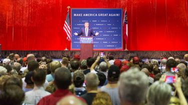 Trump discursa no palanque, observado por dezenas de pessoas