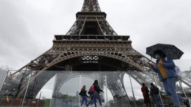 A woman wearing a face mask passes by the Eiffel Tower, 14 March